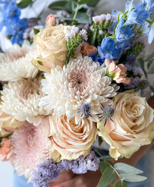 Bouquet of flowers with a mix of colors including white, pink, blue, and green.